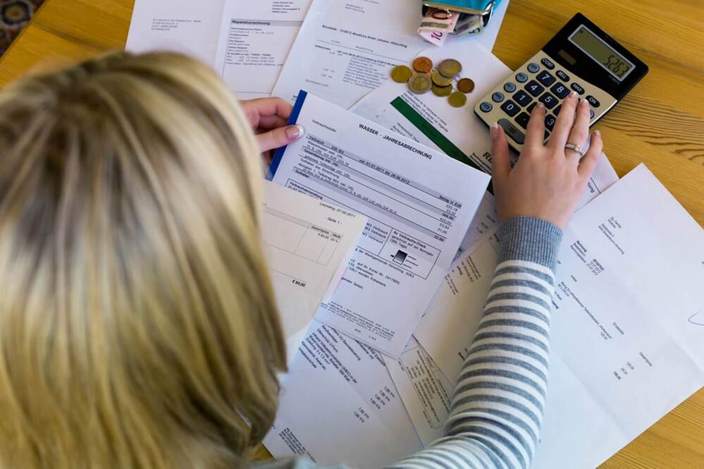Mulher usando calculadora para organizar finanças
