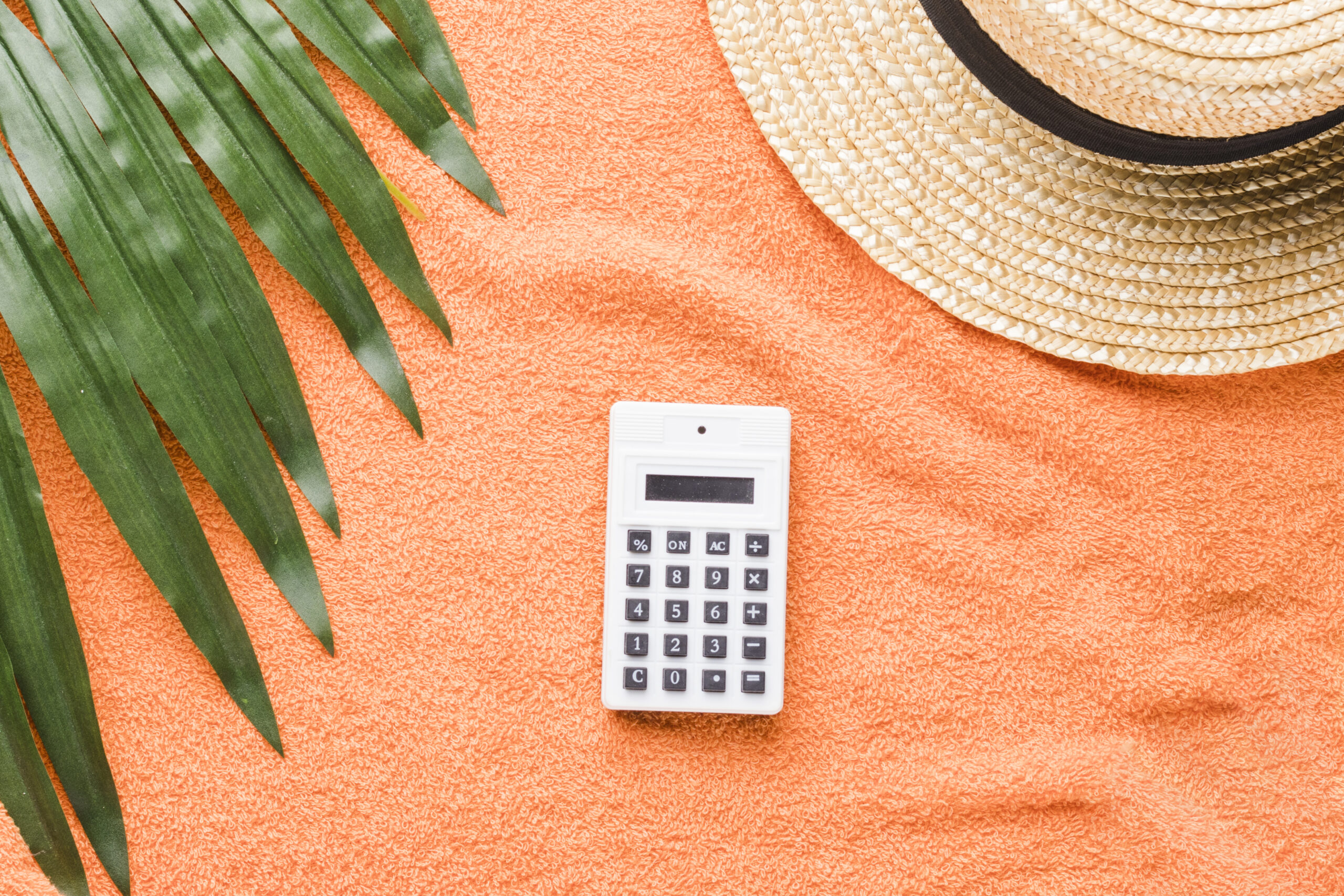 calculadora e chapeu de praia em fundo laranja